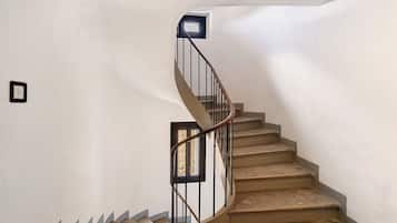 Una escalera de caracol con barandilla y una lámpara en la pared.