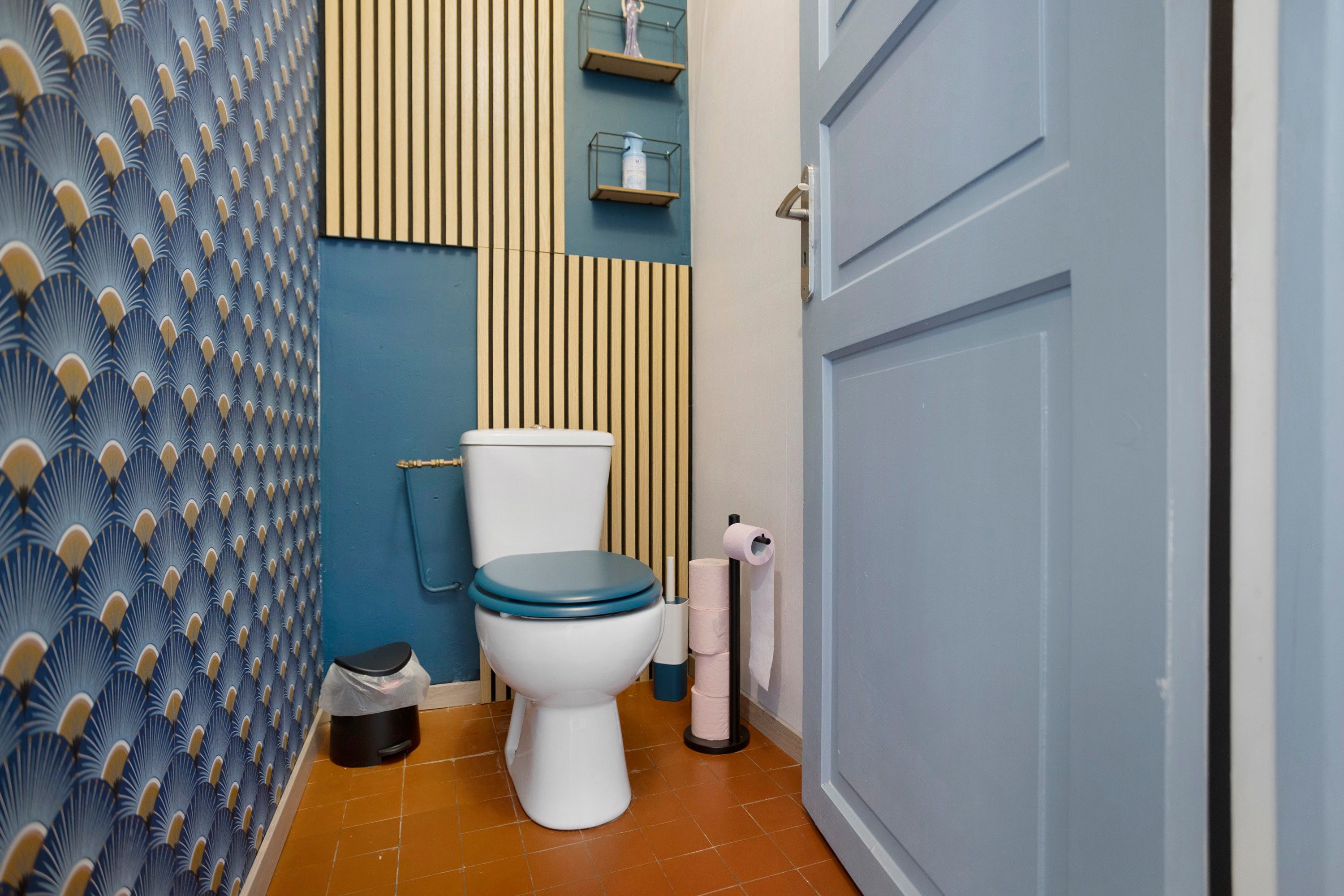 Ein Badezimmer mit Toilette, Mülleimer und Toilettenpapierhalter.