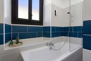 Un baño moderno con bañera, ducha y ventana.
