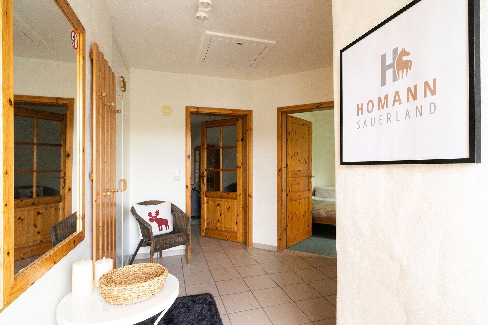Un interior de hotel con puertas de madera, un cartel enmarco, una cesta de mimbre y una silla con un cojín rojo.