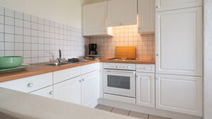 A kitchen with white cabinets, a wooden countertop, a stove, and a sink. - Apartment 'Ferienhof Homann Sauerland - LH 6 Balcony and Wi-Fi' (Brilon)