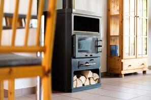 A wood-burning stove with a glass door and a storage compartment for firewood. - Ferienhaus 'Homann Sauerland – LH 2' mit Gemeinschaftsterrasse und WLAN (Brilon)