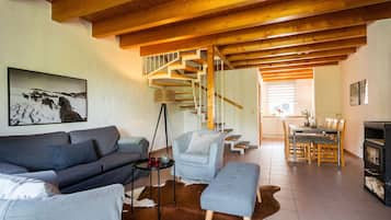 Una sala de estar con sofá, una mesita de centro, chimenea y una escalera que lleva a otra habitación.