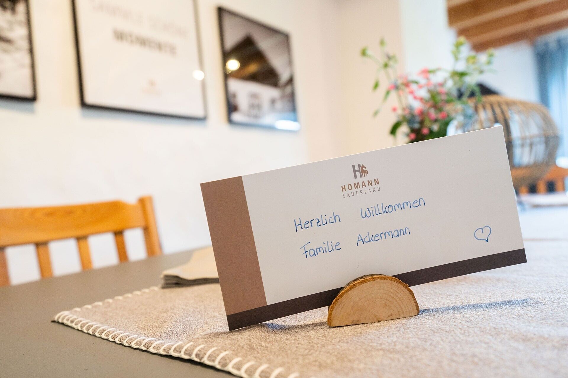 A hotel reception desk with a sign that reads 'HOMANN SAUERLAND' and 'Herzlich Willkommen Familie Ackermann' with a heart symbol.