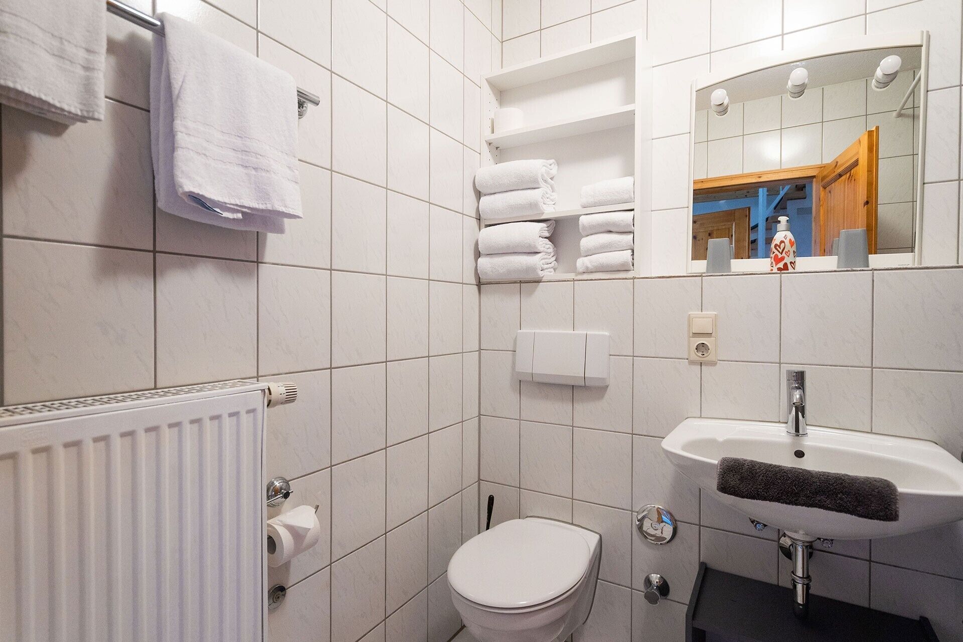 Ein Badezimmer mit Toilette, Waschbecken, Handtuchhalter und Spiegel.