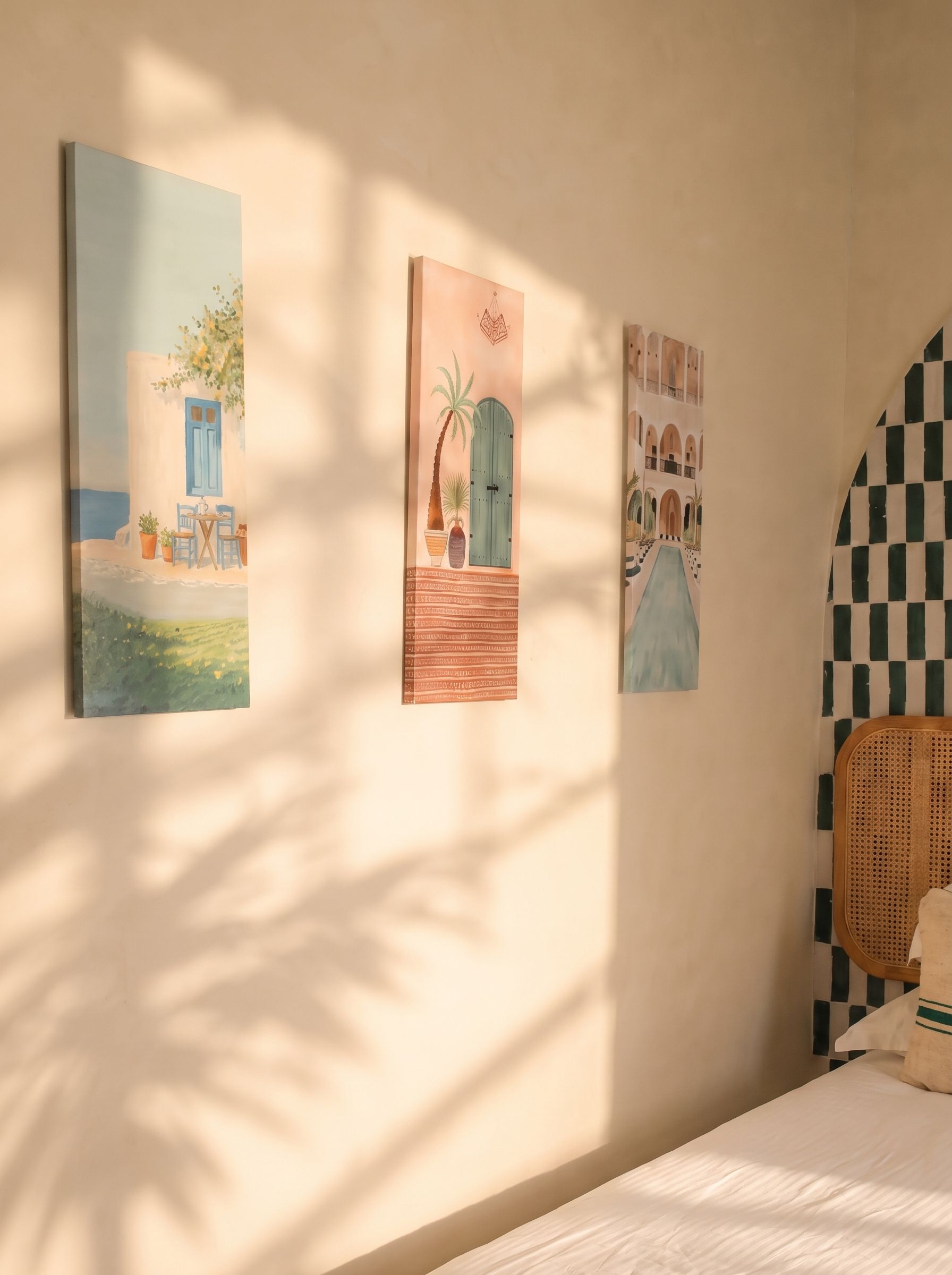 Une pièce avec un lit, un mur orné de trois tableaux et un motif à carreaux sur le mur.
