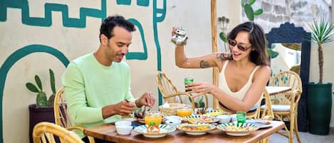 A dining table with plates of food, a teapot, and a green glass.