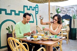 Un tavolo da pranzo con piatti di cibo, un teiera e un bicchiere di vetro verde.
