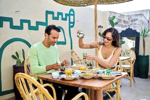 A dining table with plates of food, a teapot, and a green glass.