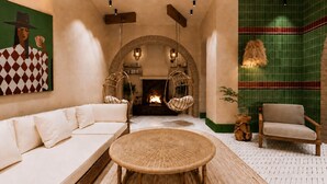 A modern living room with a sofa, a round wicker table, and hanging chairs. - StayHere Essaouira Heritage – Dar El Qadima (Essaouira)