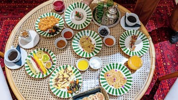 Mesa redonda con diversos platos y bebidas, evocando un ambiente de comedor compartido.