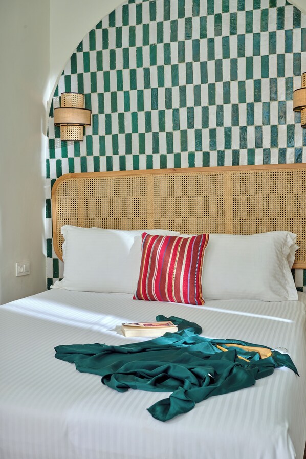 A bed with a checkered wall pattern, a rattan headboard, and a striped pillow.