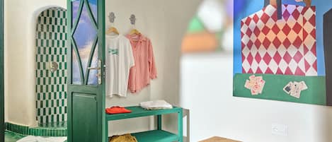 A room with a green door, a checkered wall, a white shirt, a striped shirt, and a painting of a woman with cards.