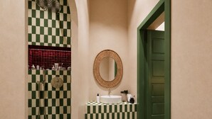 A narrow hallway with a checkered floor, a sink with a mirror, and a shower area. - StayHere Essaouira Heritage – Dar El Qadima (Essaouira)