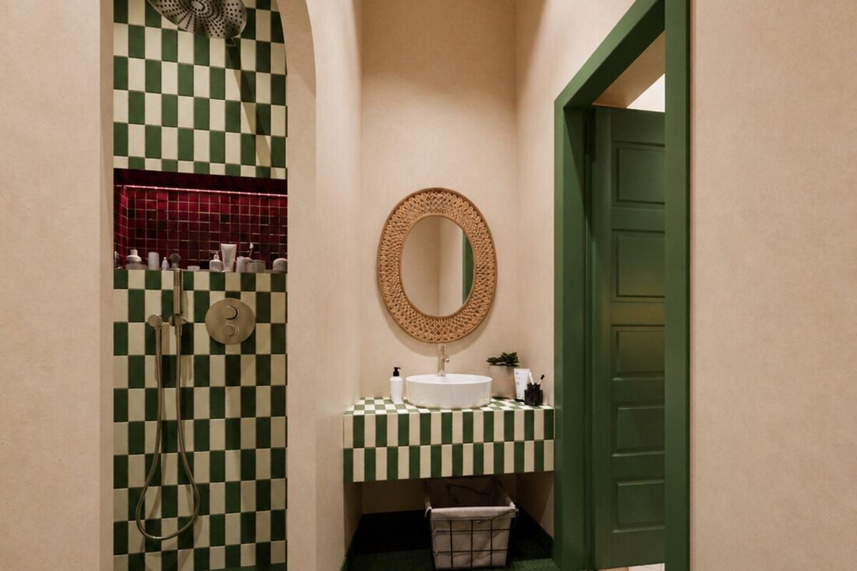 A narrow hallway with a checkered floor, a sink with a mirror, and a shower area.