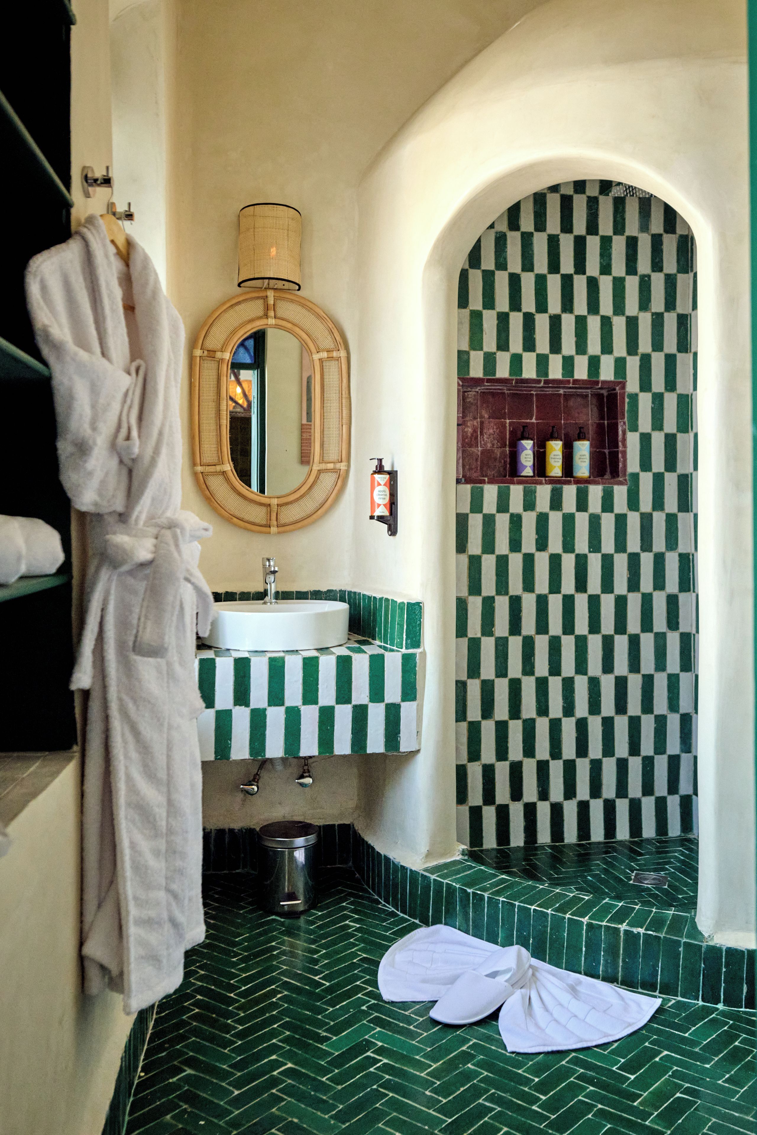 A bathroom with a checkered floor, a round mirror, a sink, and a towel rack.
