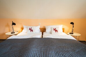 A double bed with a grey quilted cover, two white pillows with a moose design, and two bedside lamps on matching nightstands. - Ferienwohnung 'Ferienhof Homann Sauerland - BH 6' (Brilon)