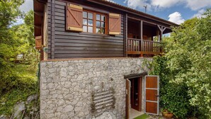 Una casa rústica de madera con un acceso de pared de piedra y un balcón de madera.