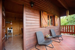 A wooden cabin with a porch, two wicker chairs, a small table with a vase, and a sign that reads 'HOME'. - Quinta Do Castelo - Family Country House with Mountain View, Wi-Fi and Air Conditioning (Lourinhã)