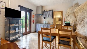 Una cocina con pared de piedra, una mesa de comedor con sillas, un refrigerador y un lavamanos.