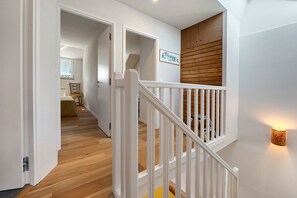 A staircase with white railings leading to a landing with a wooden wall and a framed picture. - House 'Charmante maison' with Terrace, Garden and Wi-Fi near the Sea (Arzon)