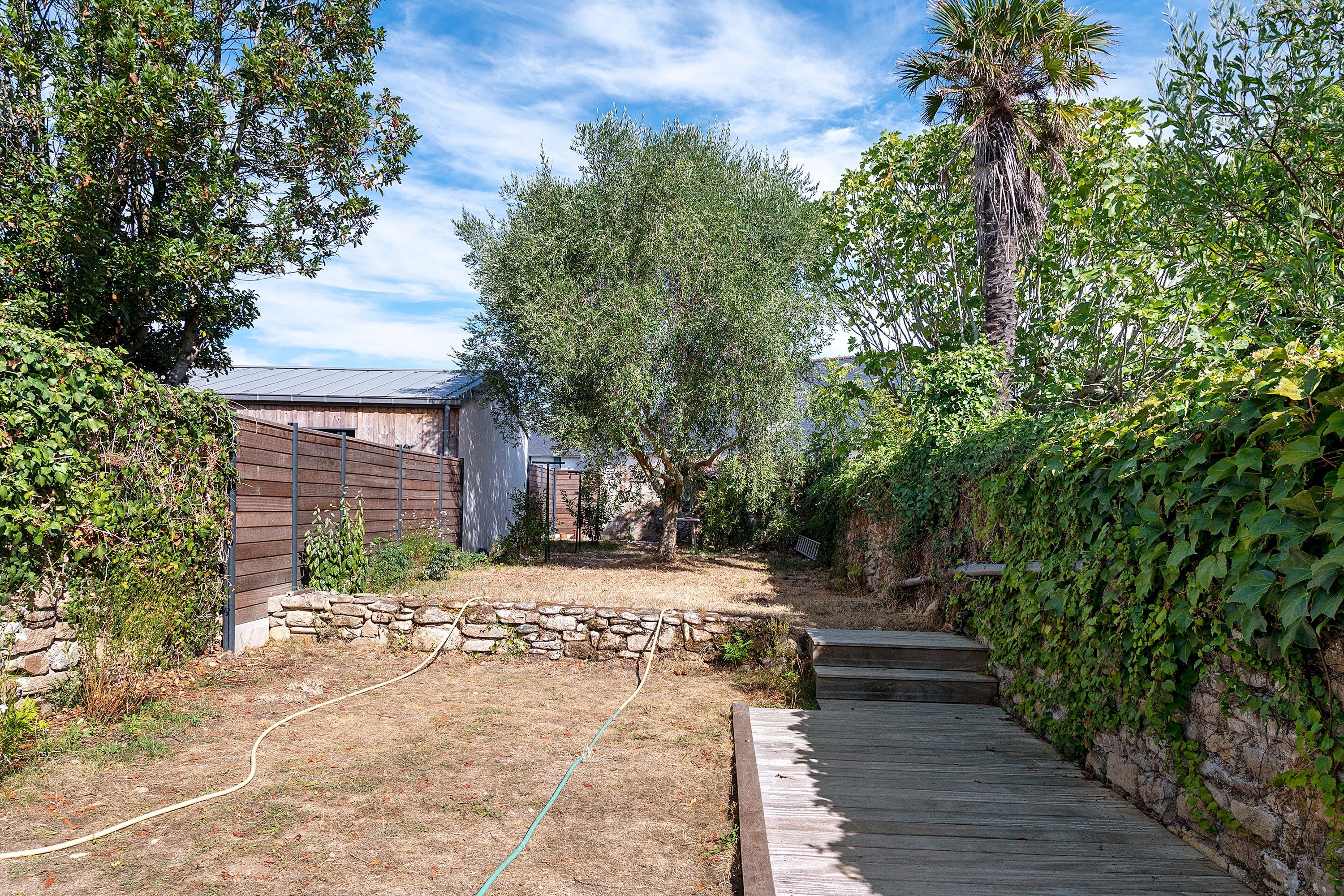 Ein Garten mit einer Steinmauer, einer Holzterrasse und einem Gartenbereich.