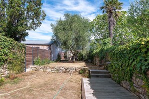 A backyard with a stone wall, a wooden deck, and a garden area.