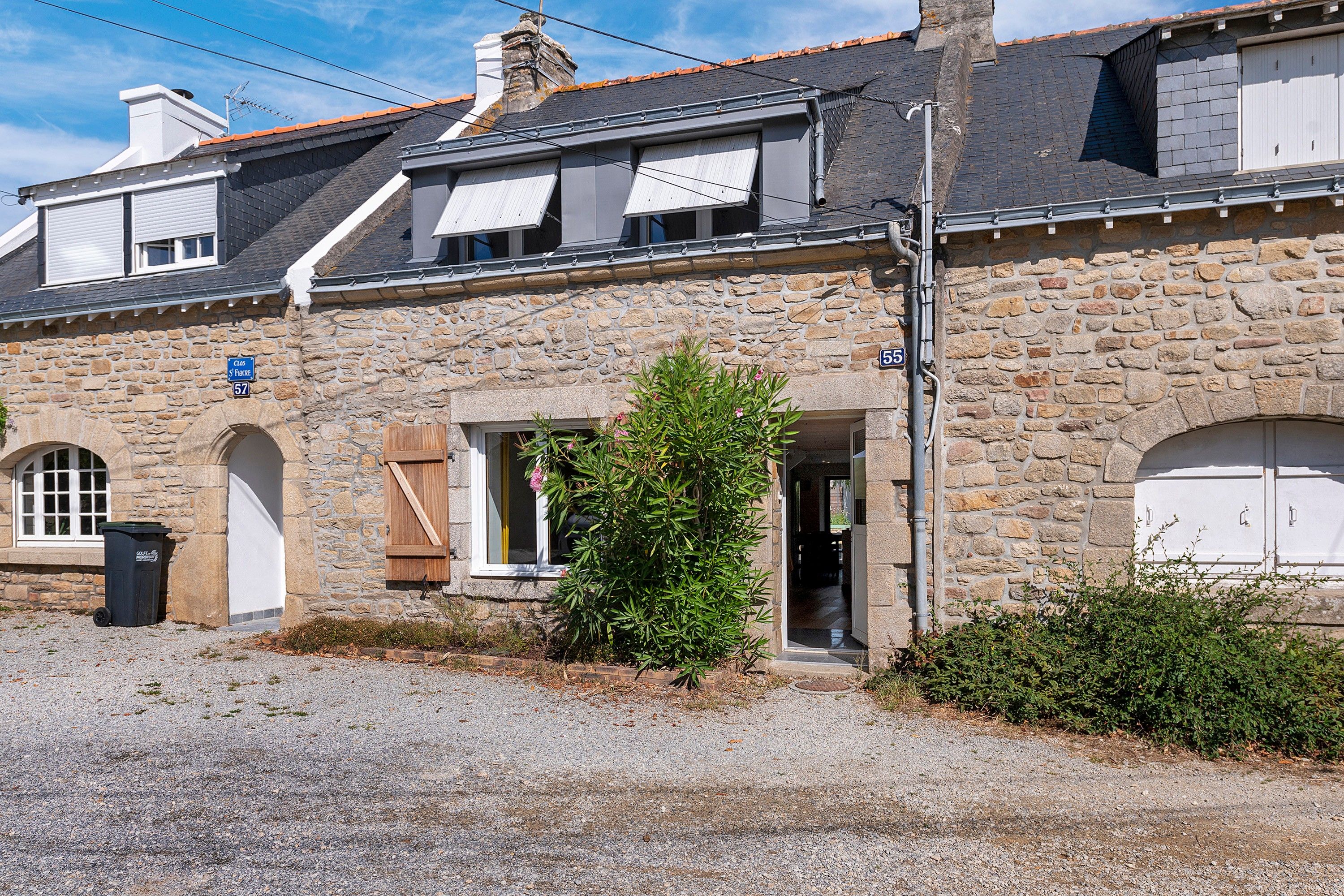 A stone building with a gravel driveway, a wooden door, and a small window.