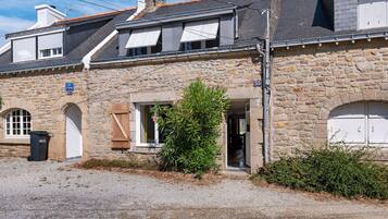 A stone building with a gravel driveway, a wooden door, and a small window.