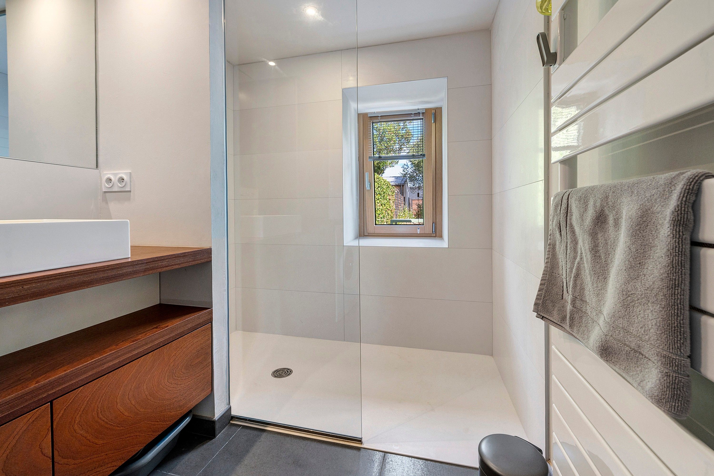 Une salle de bain moderne avec une douche, une fenêtre et un porte-serviettes.