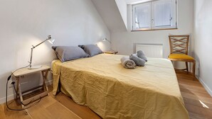 Ett sovrum med en säng, sänglampor, en stol och ett fönster med persienner.