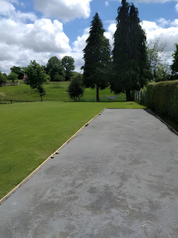A concrete pavement leading to a grassy area with trees and a hedge.