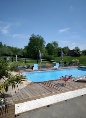 A swimming pool with lounge chairs and a wooden deck.