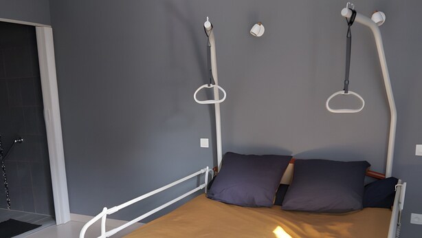 Een moderne slaapkamer met een bed, kussens en een hoofdbord.