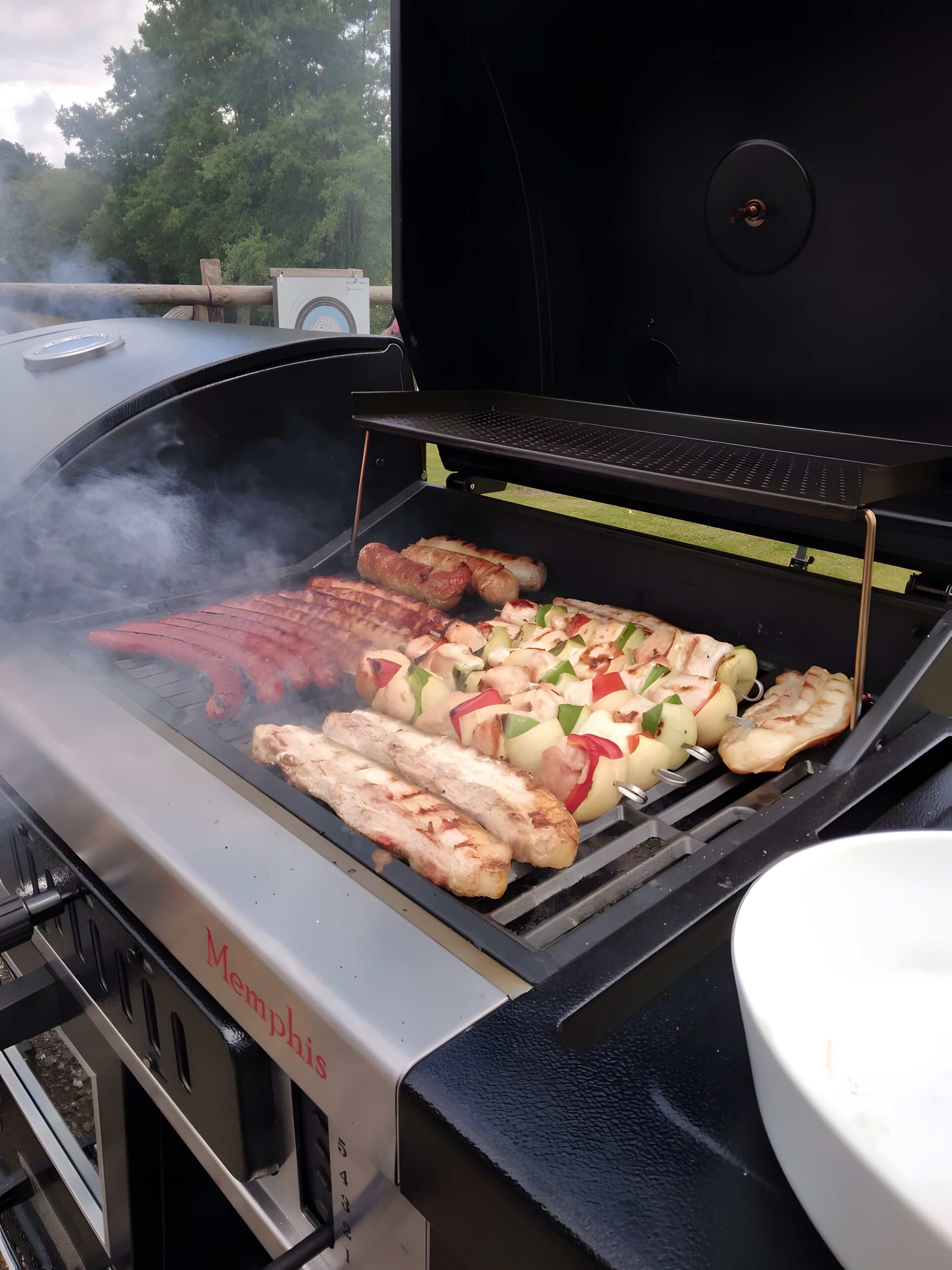 Een barbecue met verschillende vleessoorten en groenten die worden bereid.