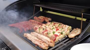 Een barbecue met verschillende vleessoorten en groenten die worden bereid.