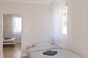 A small, single-bed room with a wooden floor, a bedside table, and a window with sheer curtains. - Apartment "C & D II" with Shared Terrace and Wi-Fi (Bad Kissingen)