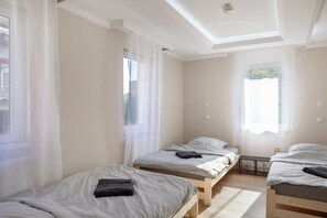 Ein Zimmer mit drei Einzelbetten, jedes mit einem Kopfkissen und einem Handtuch.
