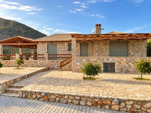 A stone building with a tiled roof, a wooden porch, and a stone staircase leading to a covered area. - Panoramic Sea View Villa near Galaxidi (Gerakofono Galaxidi)