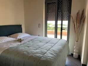 A bedroom with a bed, a window with blinds, and a vase with dried plants. - Panoramic Sea View Villa near Galaxidi (Gerakofono Galaxidi)