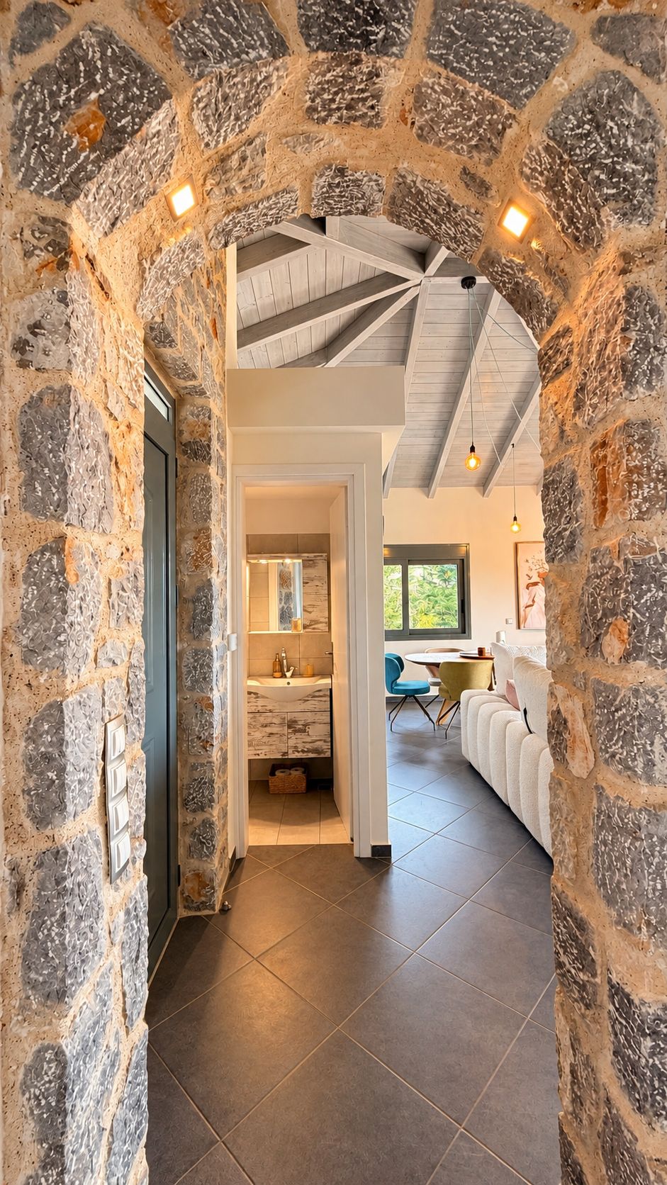 A stone archway leading to a modern bathroom with a sink and mirror.