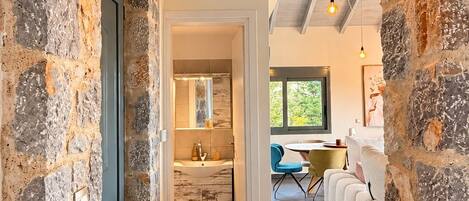 A stone archway leading to a modern bathroom with a sink and mirror.