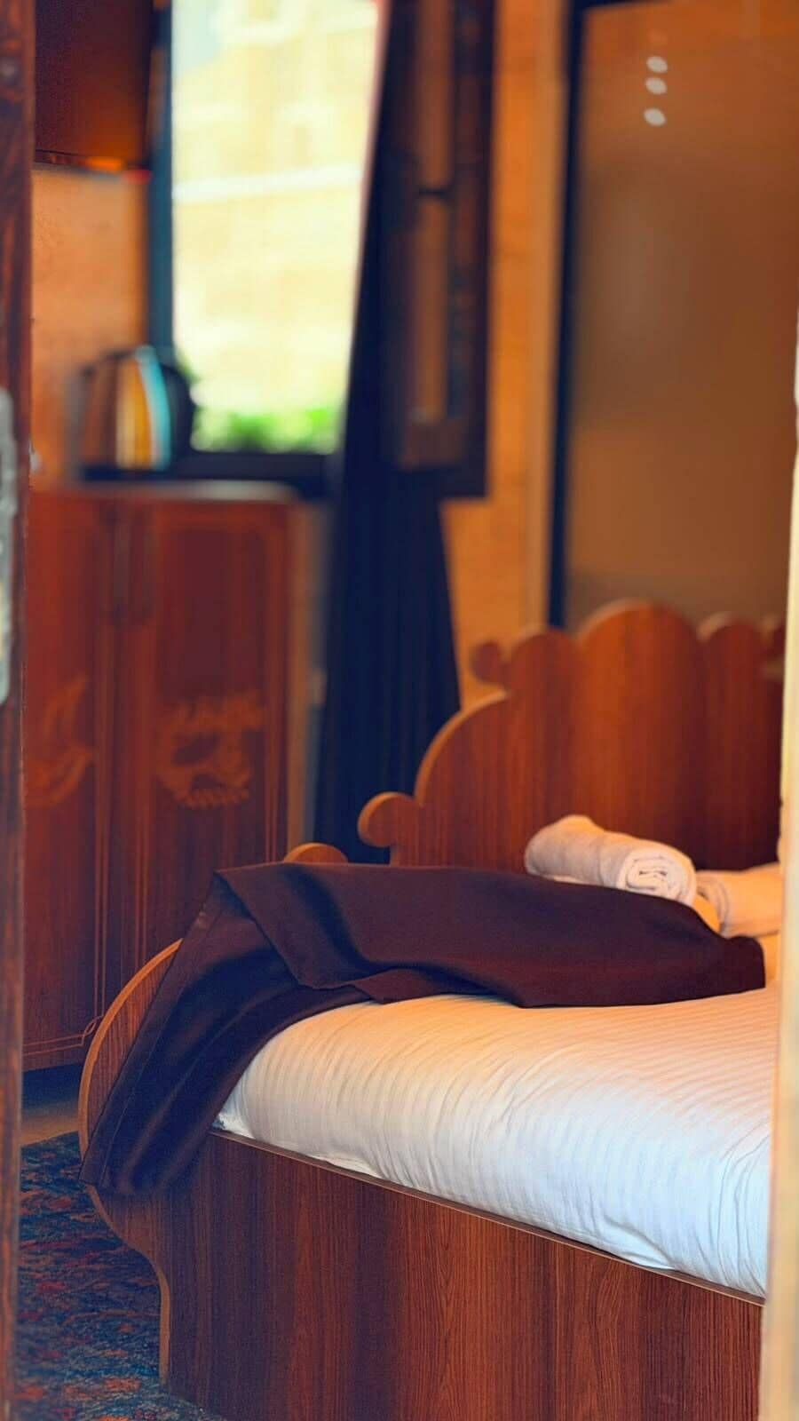 Una habitación de hotel con una cama, cabecera de madera y una ventana con cortinas.