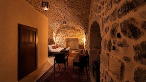 Une pièce aux murs de pierre, avec un lit, une table et des chaises.