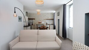 Ein Wohnzimmer mit einer Couch, einem Esstisch und einer Küche im Hintergrund.