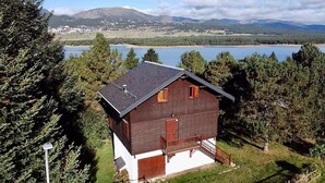 Eine Holzhütte mit einem Balkon, umgeben von Bäumen und Blick auf einen See.