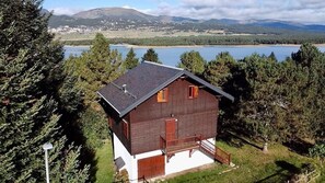 Eine Holzhütte mit einem Balkon, umgeben von Bäumen und Blick auf einen See.