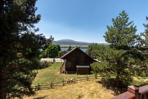 A rustic cabin with a wooden deck, surrounded by trees and a view of a lake and mountains. - Le Chalet Cosy du Lac - à 900m du lac (Matemale)