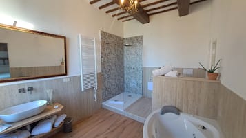 A modern bathroom with a large bathtub, a shower, and a vanity with a mirror.