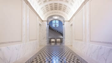 A marble-floored corridor with a geometric pattern leading to a staircase.